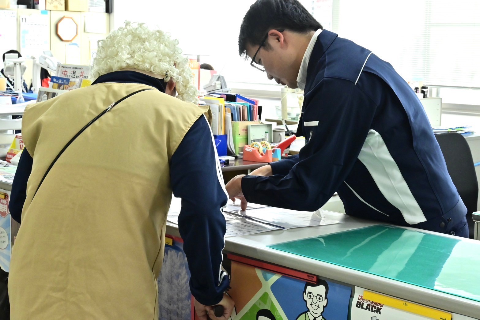 高齢者役が小豆島町職員にバスの時刻を教えてもらう様子の写真