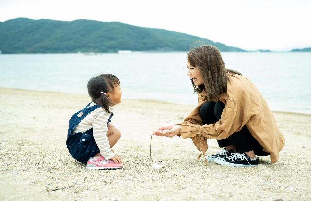 親子が砂浜で向き合って笑いあっている写真です