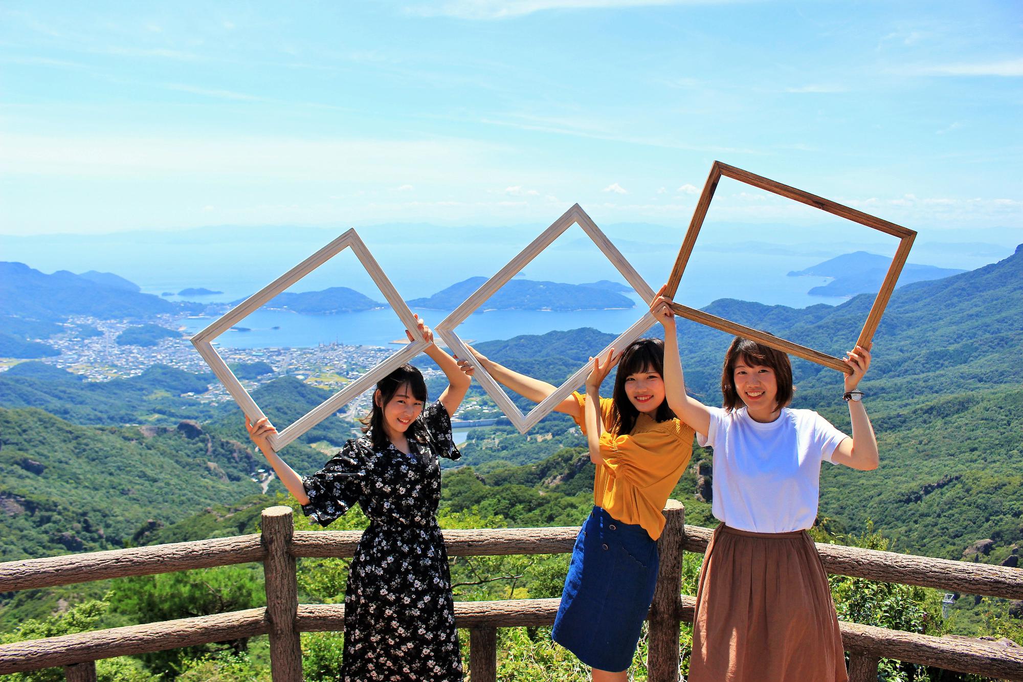 瀬戸内海をバックに寒霞渓山頂でナチュラルフレームを持った女性3人の写真