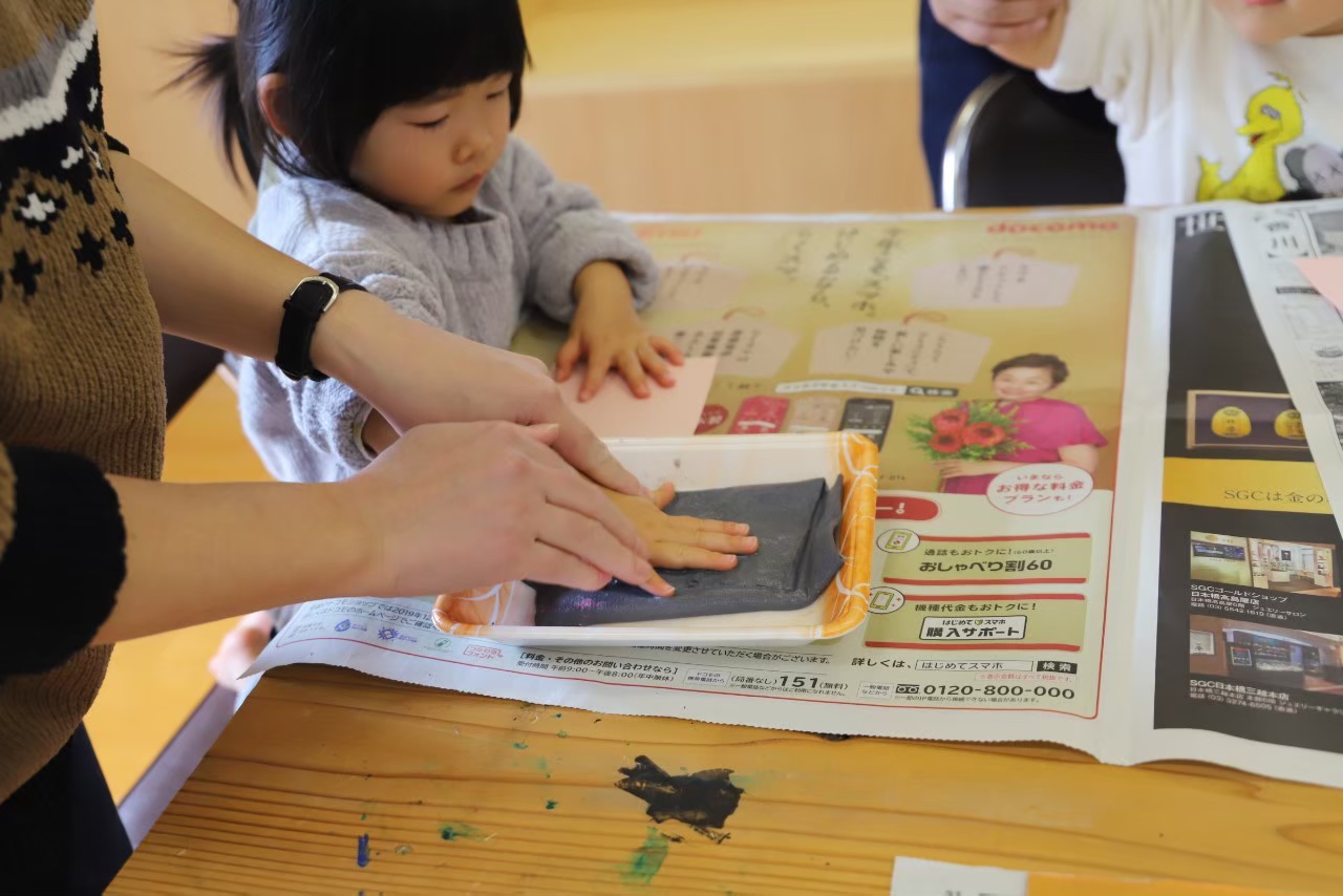 子どもが手形のはんこをして工作している画像
