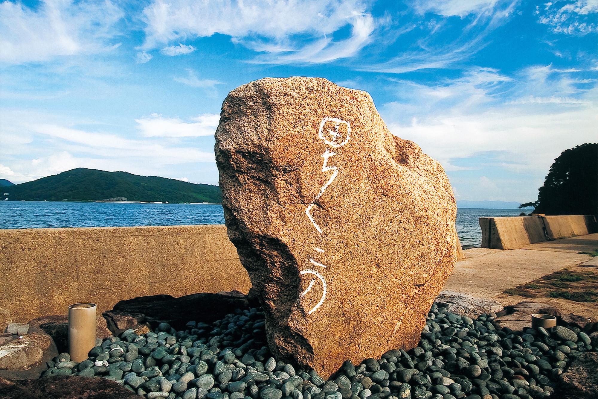 海と空を背景に砂利石の上に「田ちくこの」と刻まれた残石がひとつある