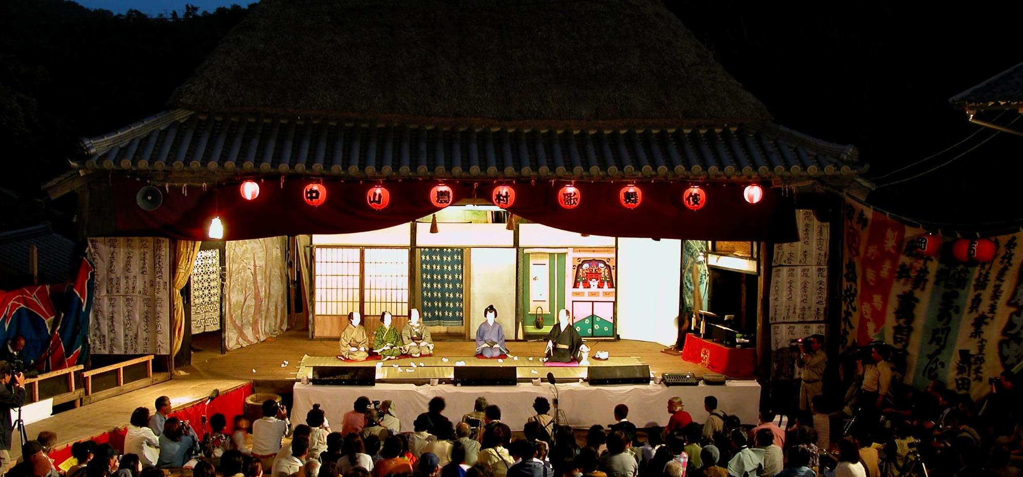 薄暗い夕暮れ時に大勢の観客の前で中山歌舞伎が上演されている