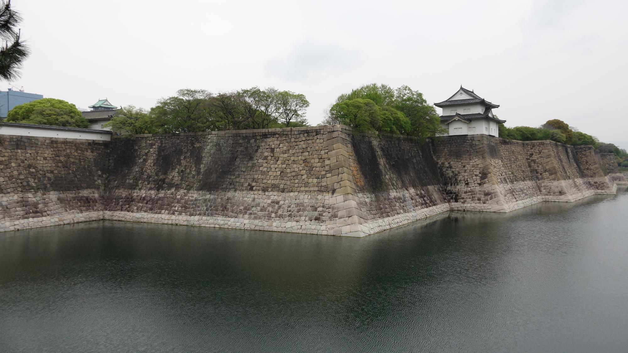 水の張った堀の向こうに大坂城の石垣と、遠くに大坂城天守閣の一部がみれる