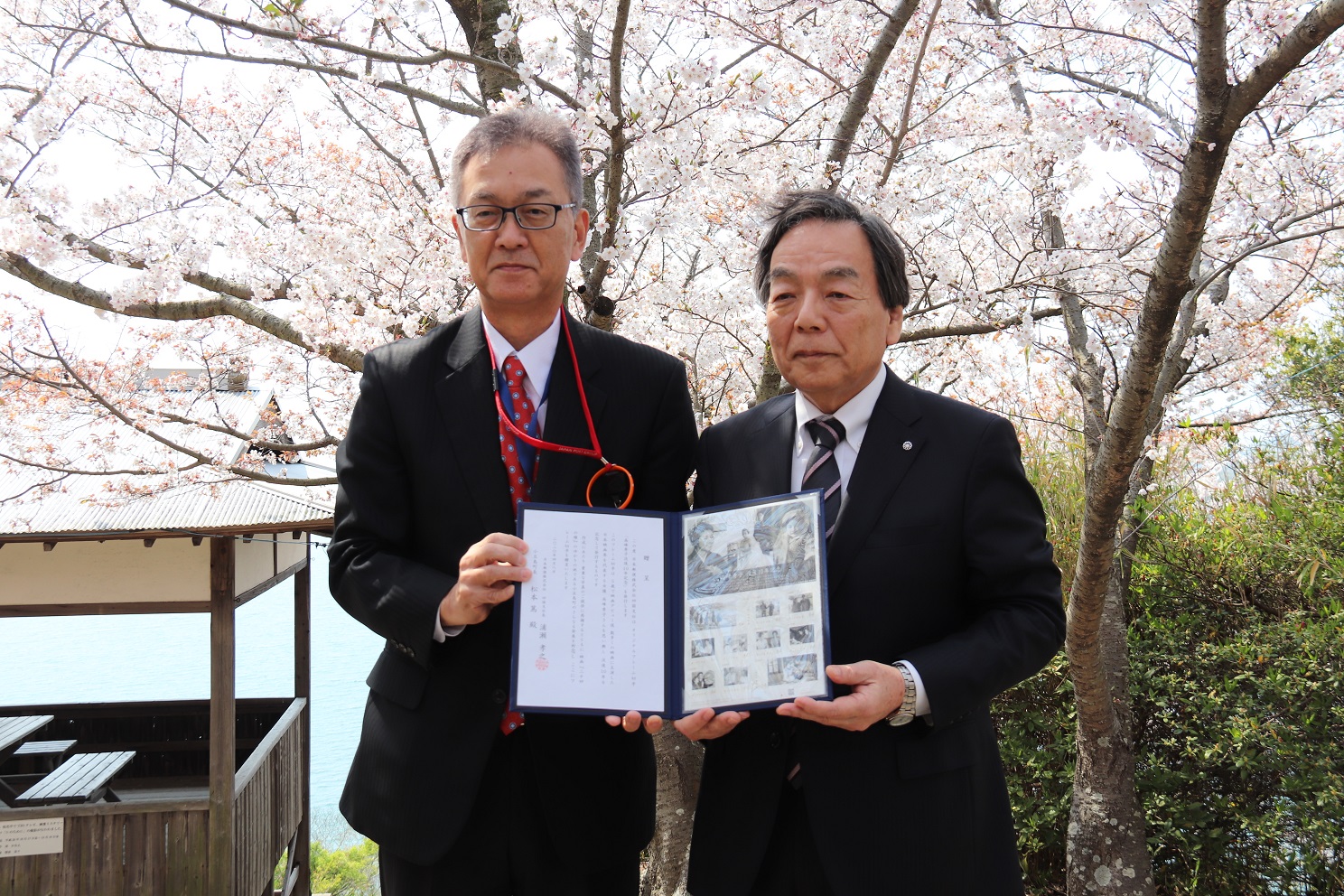 記念切手贈呈式にて「オリジナルフレーム切手」を持って日本郵便の職員と記念撮影をする松本町長の写真