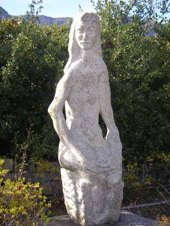 髪の長い女性が座っている姿の石彫の写真