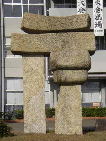 四角い棒状の2本の石の上に丸い石が2つ、その上に平の石が2つ乗せてある石彫の写真