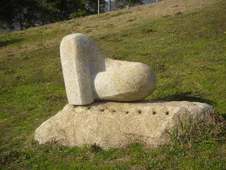 中央に穴が点在している長方形の石の土台の上に、ハートを横にしたような石彫が置かれている写真