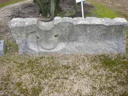 横長の長方形の石彫の側面に、スマイルマークのような形に掘られている石彫の写真