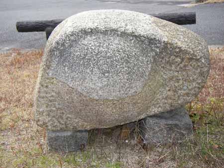 2つの土台の石の上に、丸みを帯びた三角の石が置かれている石彫の写真