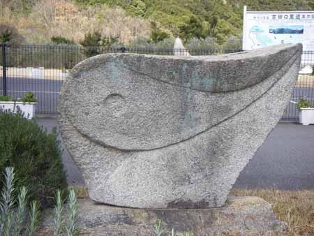 表面に勾玉のような模様が彫られ、右上に尾が上がり丸みを帯びた石彫の写真