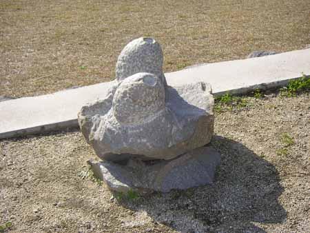 いびつな形の石に上に、丸い穴があいた卵型の形の石が2つ乗っている写真