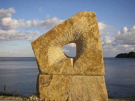 四角形の土台の石の上に、不規則な5角形の形の石の中央に穴が開いている写真