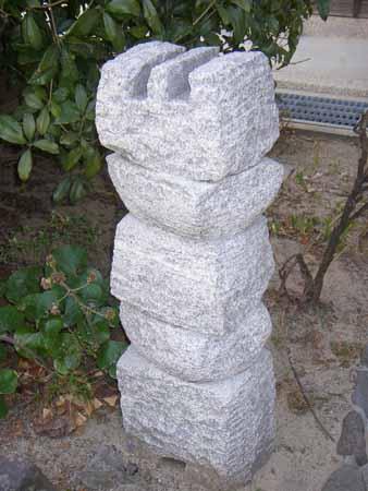四角と丸の石が交互に重なり、一番上に漢字の山のような形の石が置かれている石彫の写真