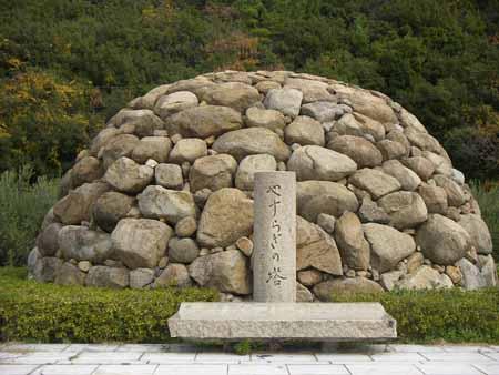 石がドームのように積み上げれておりその前に「やすらぎの塔」と掘られた円柱の石彫がある写真