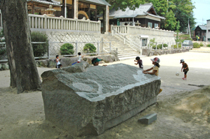 子どもたちが遊ぶ広場に置かれた長方形の巨大な石彫の写真