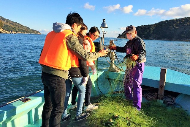 船の上で採れた魚を見ている写真