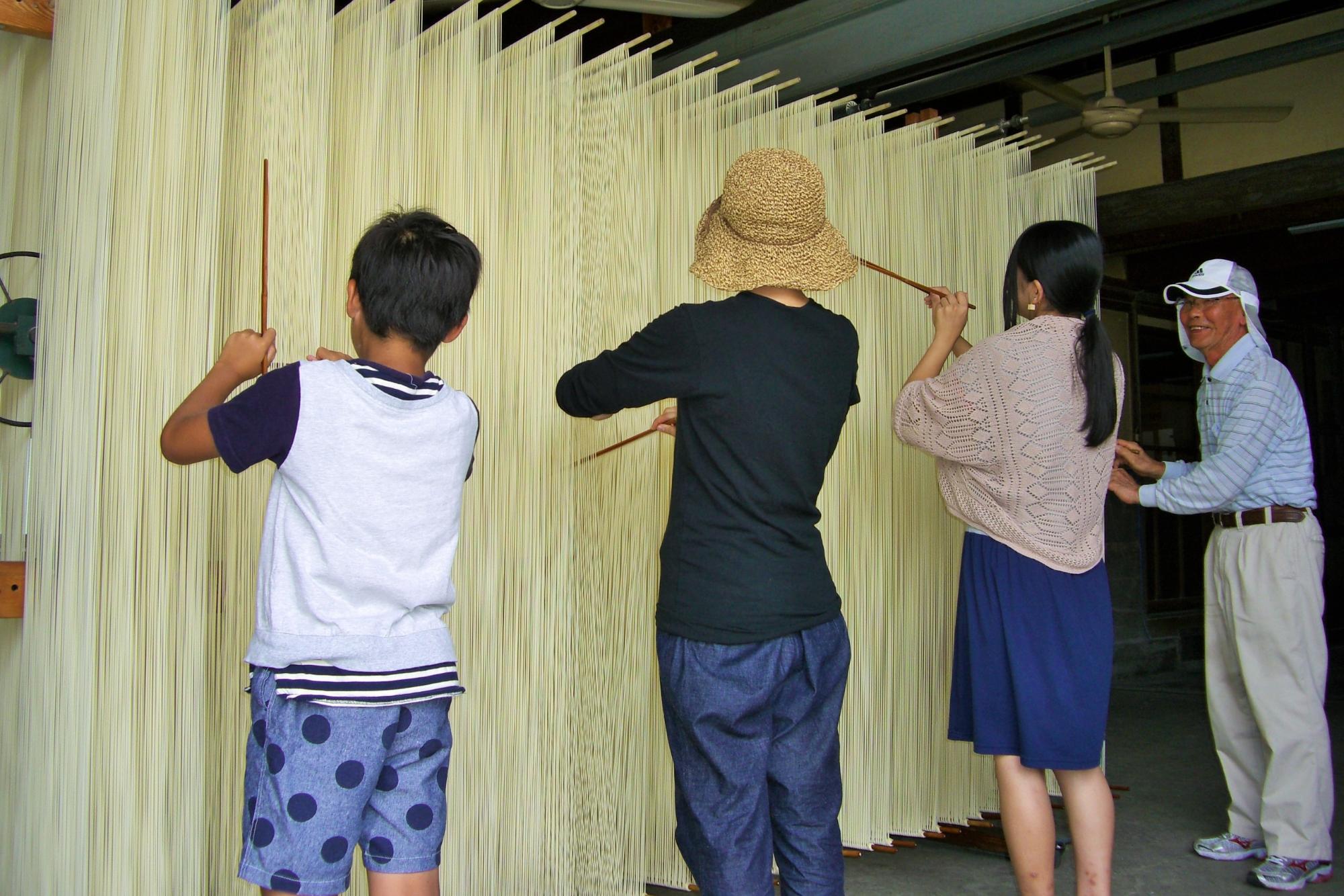 丸善製麺で素麺の箸分け体験をしておる写真