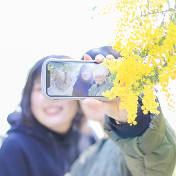 ミモザの前で自撮りをする2人の女性の写真