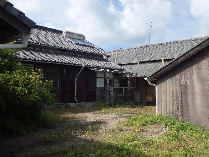 広い敷地の奥に木造平屋建ての建物が建っている写真
