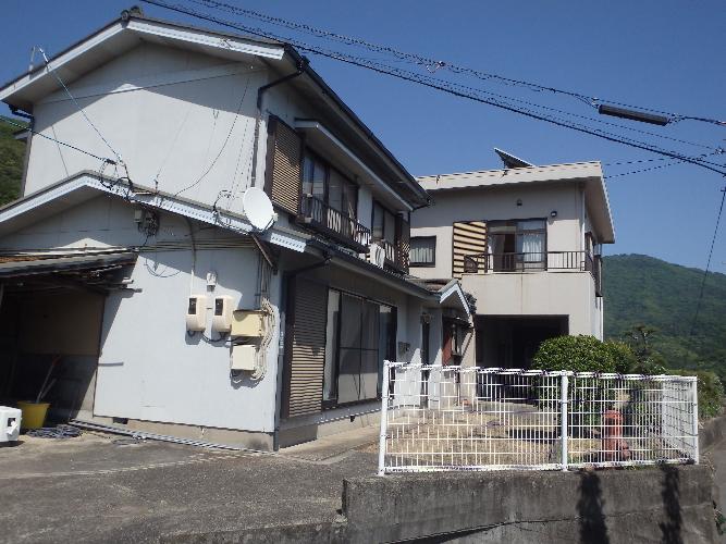 白いフェンスで囲まれ、白い外壁の木造2階建ての建物の外観写真